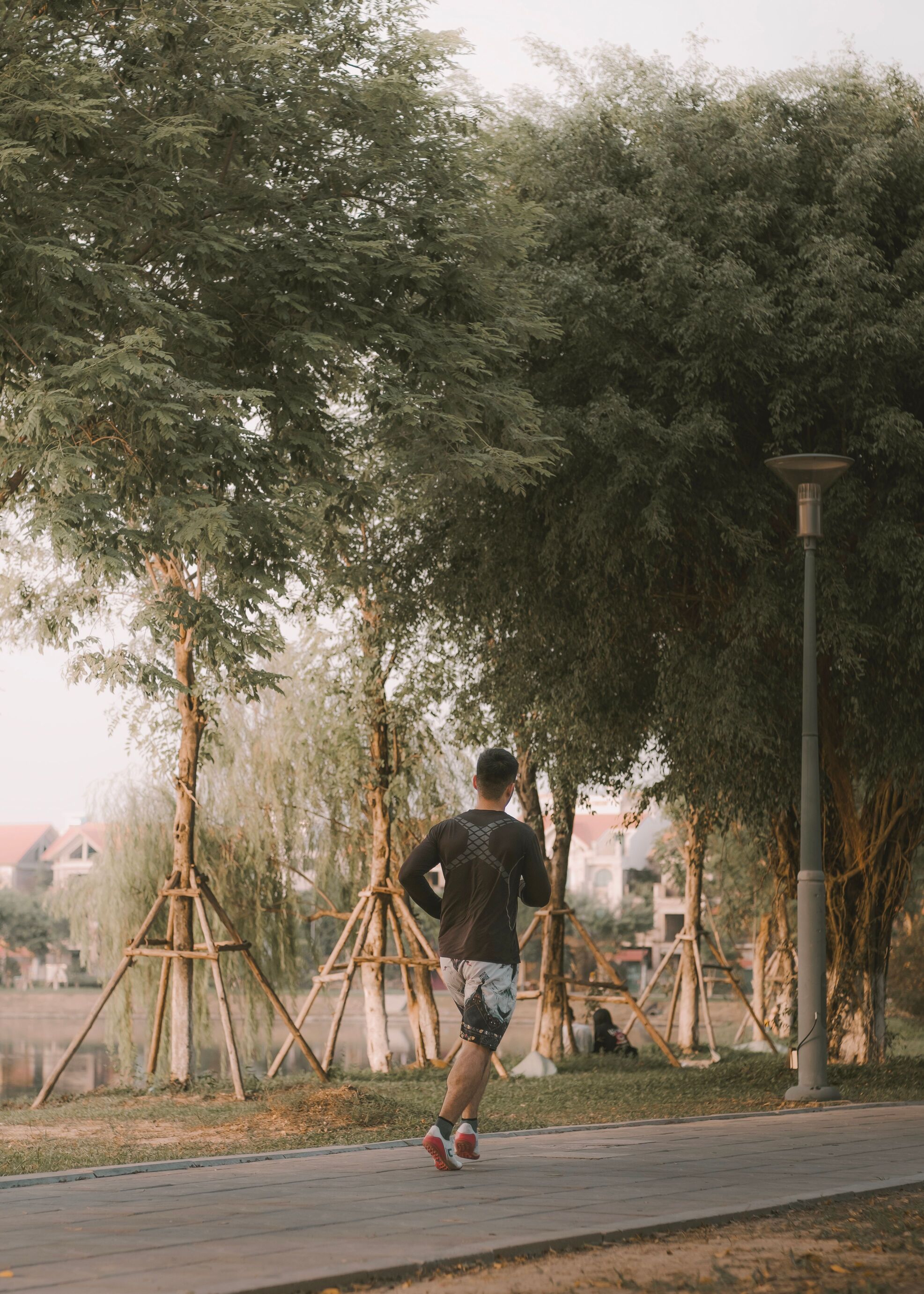 Man jogging along a tree-lined park path in the early morning