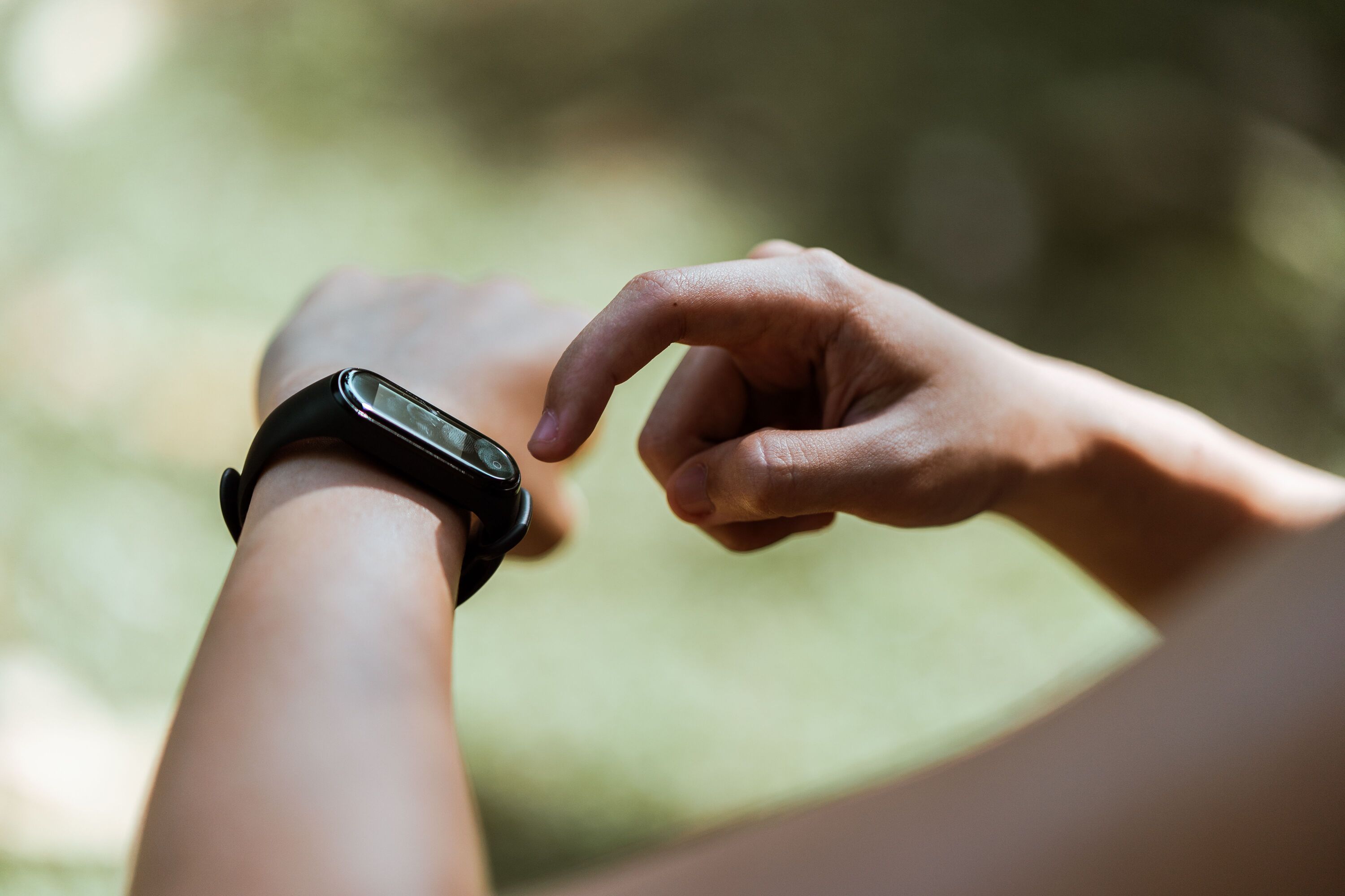 Close-up of a man tapping a black fitness tracker on his wrist outdoors